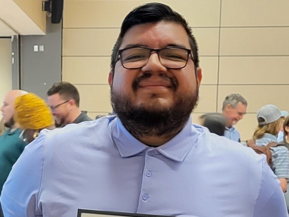 Image of Alex Hernandez smiling at camera holding certificate