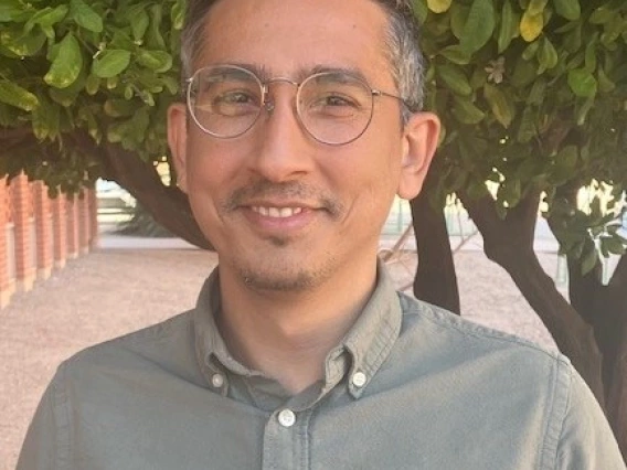 Image of a man wearing glasses smiling and looking at camera