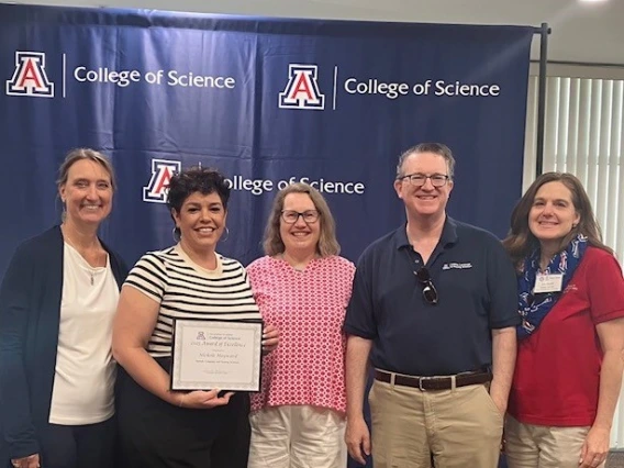 Image of five people smiling at camera; one is holding a certificate.
