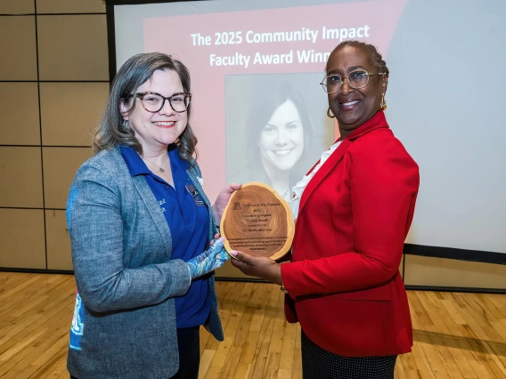 Image of two women holding an award between them and smiling at the camera