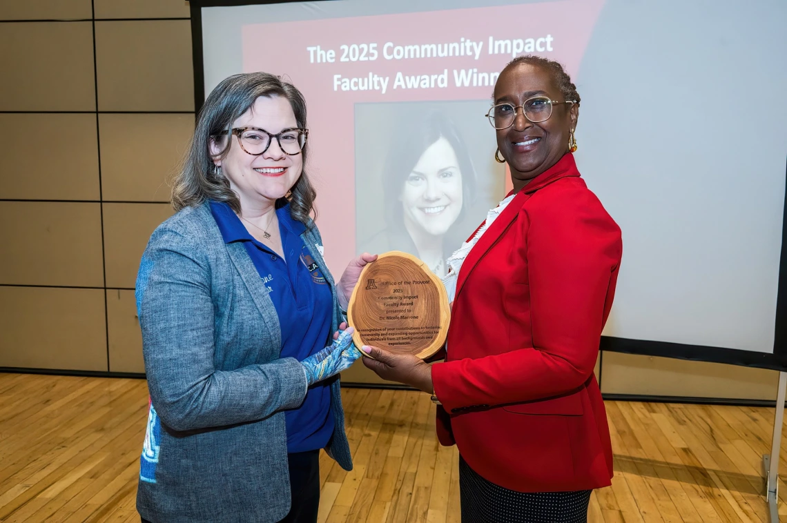 Image of two women holding an award between them and smiling at the camera