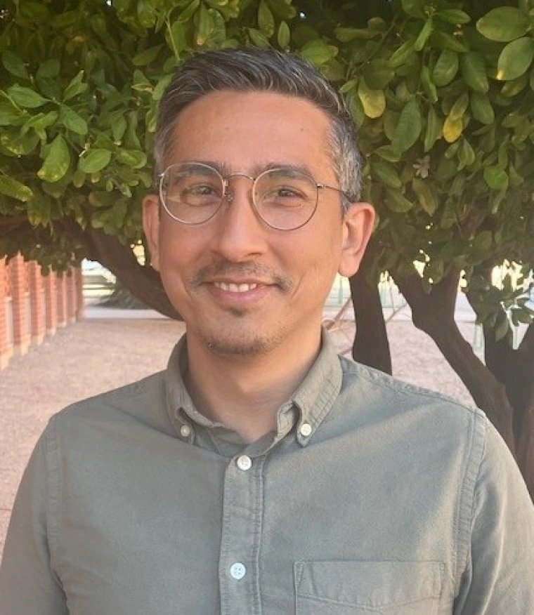 Image of a man wearing glasses smiling and looking at camera
